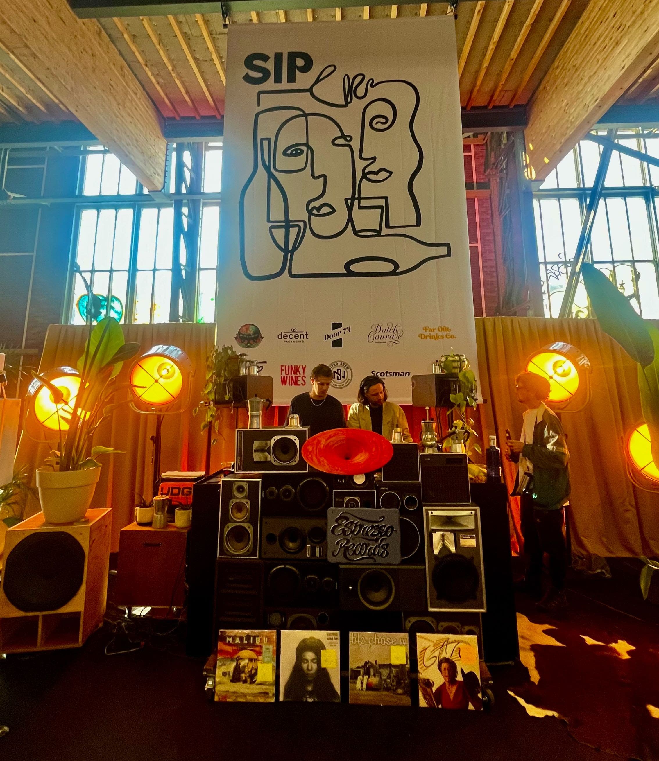 DJs behind a booth built from stacked speakers beneath the SIP banner in the NDSM warehouse