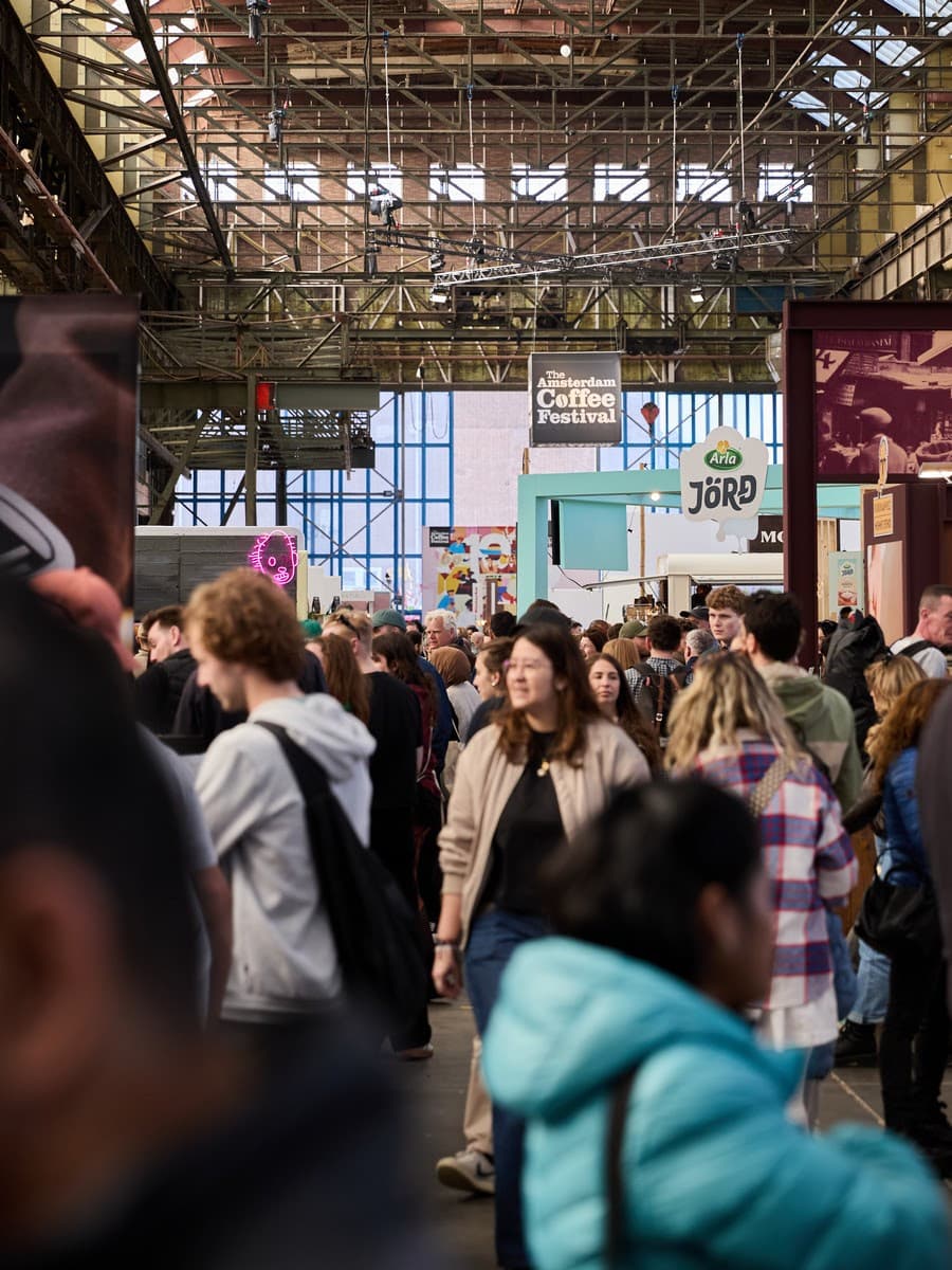 Visitors moving between stands on the busy Amsterdam Coffee Festival floor inside NDSM