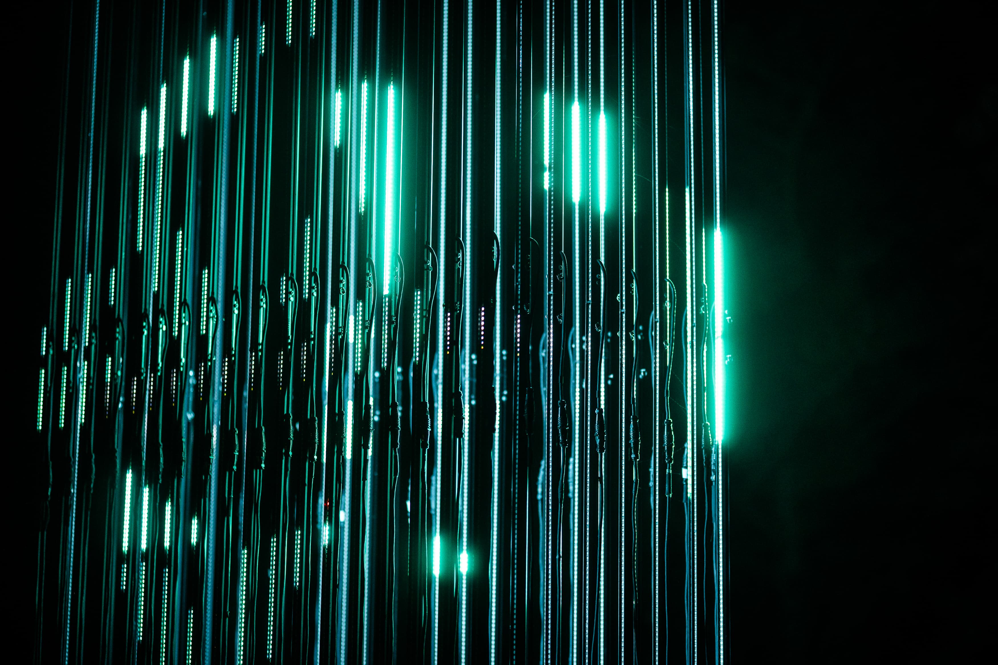 Close view of the vertical cyan LED strands and their clips inside the Schemerlicht installation