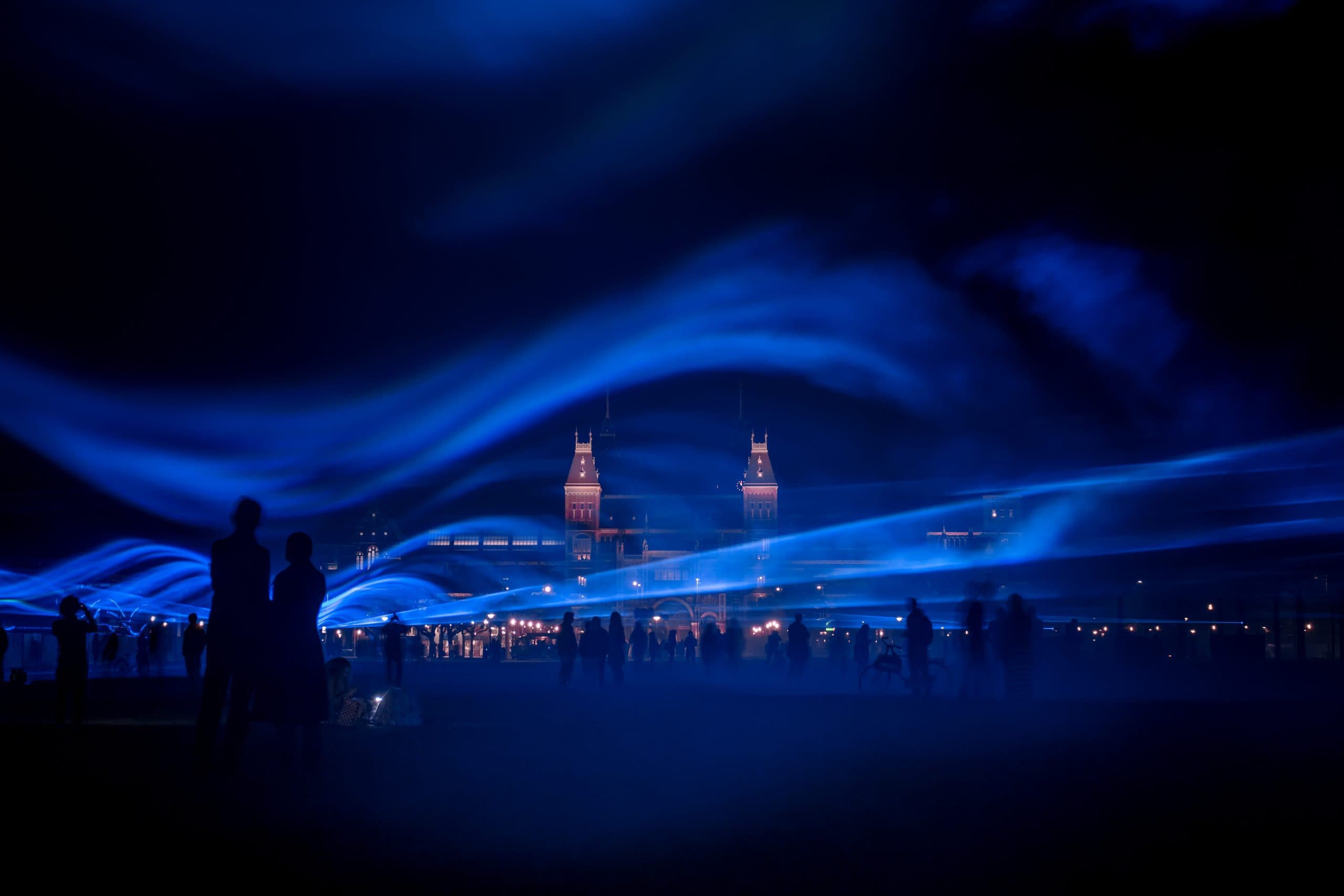 Visitors moving through blue waves of light in WATERLICHT by Studio Roosegaarde