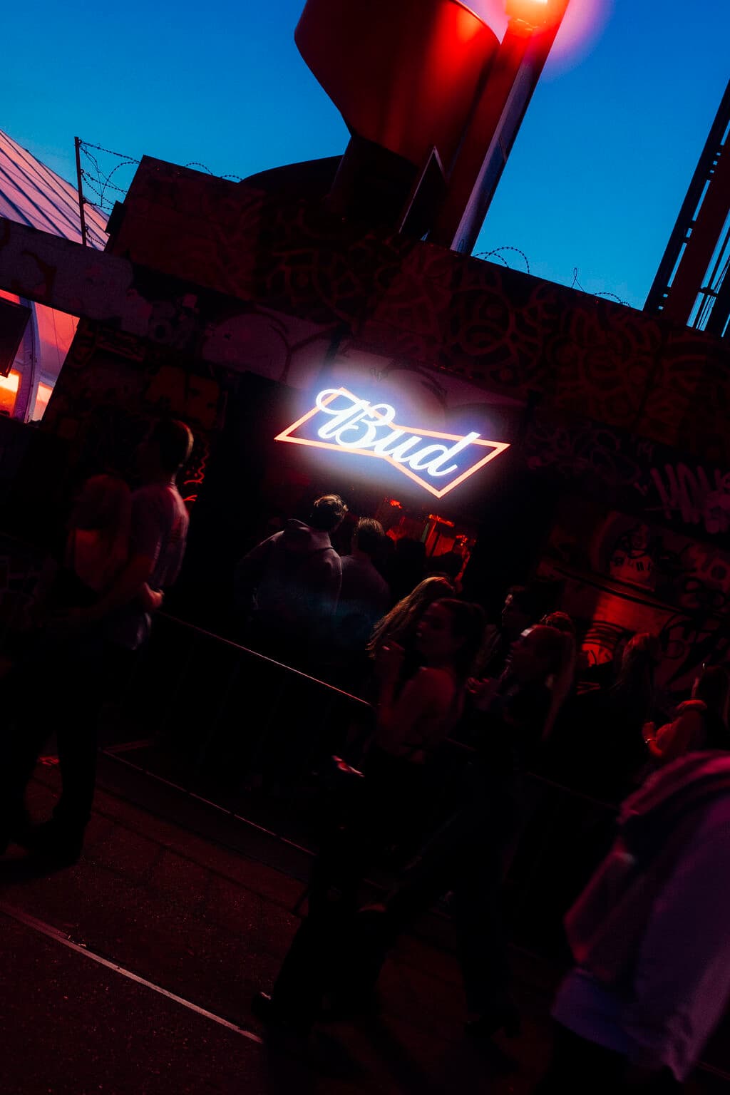 Festival guests queue beneath the illuminated BUD sign at the entrance to the NDSM crane