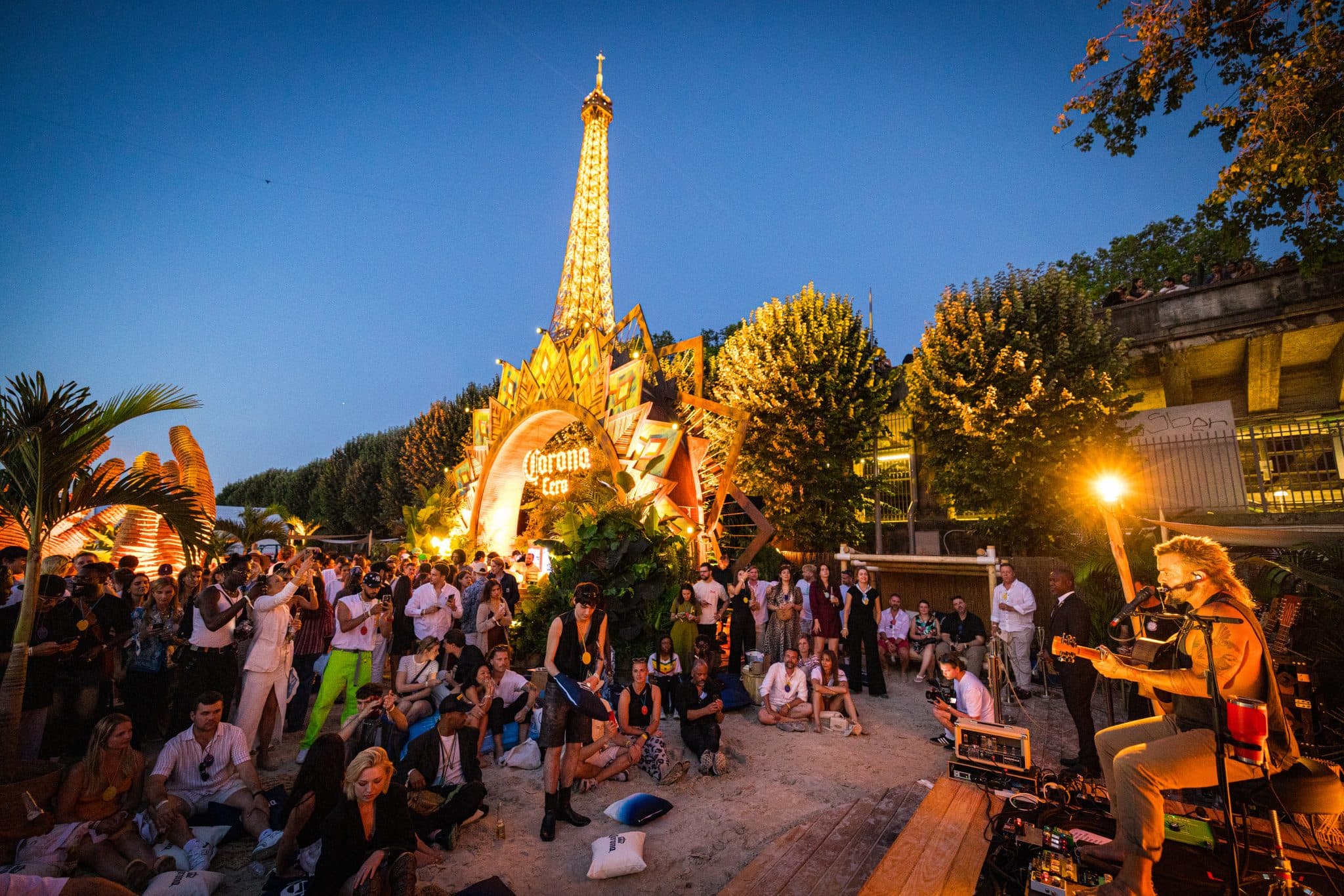 Corona Cero golden stage arch and audience beneath the Eiffel Tower at dusk